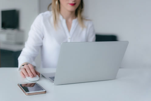 A woman intensely focused on her laptop, meticulously ensuring thorough proofreading and editing of a proposal. 